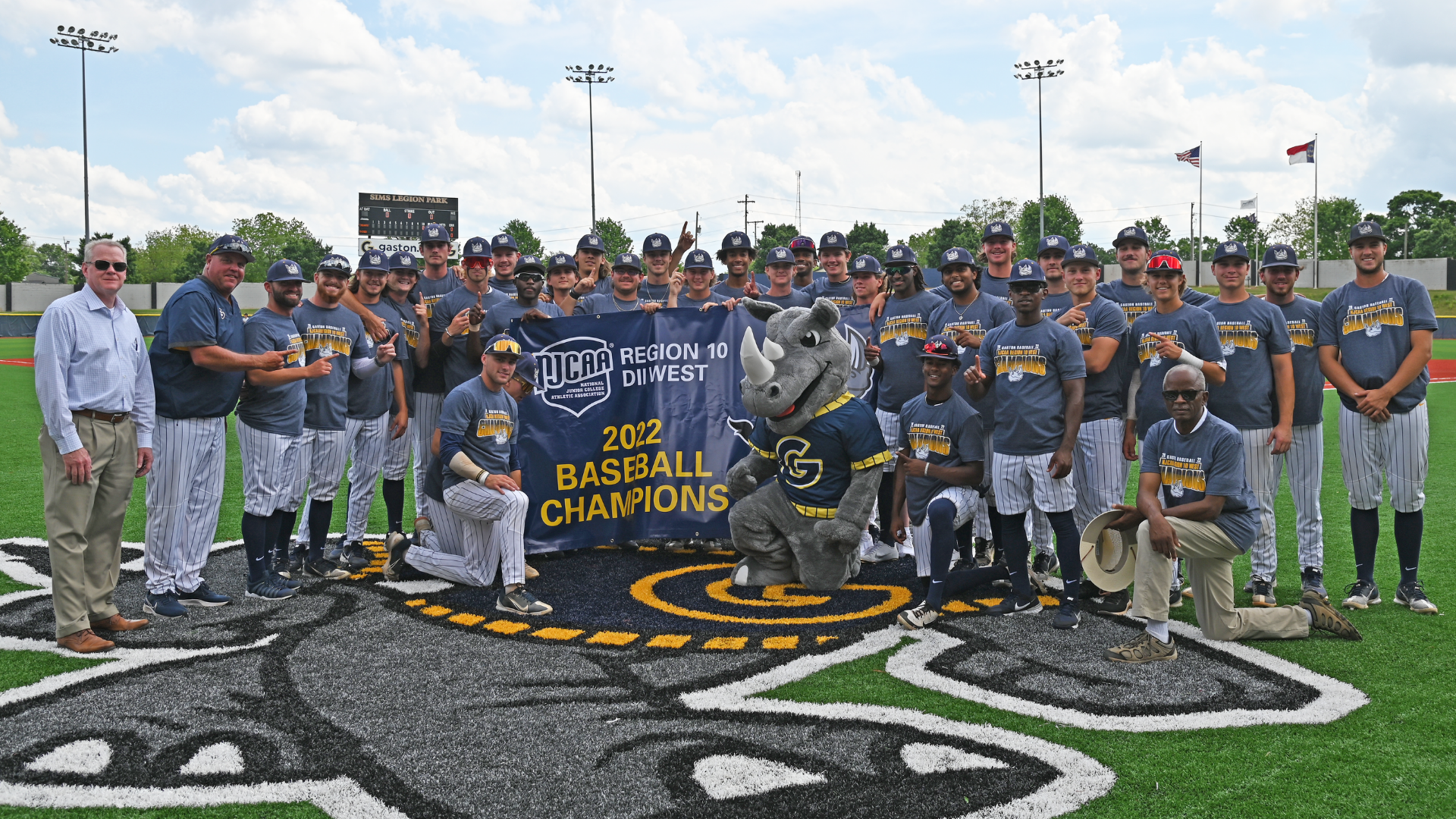 Gaston College president Dr. John Hauser (far left) with the 2022 Rhinos baseball team as they unveil their 2022 Region 10 championship banner.