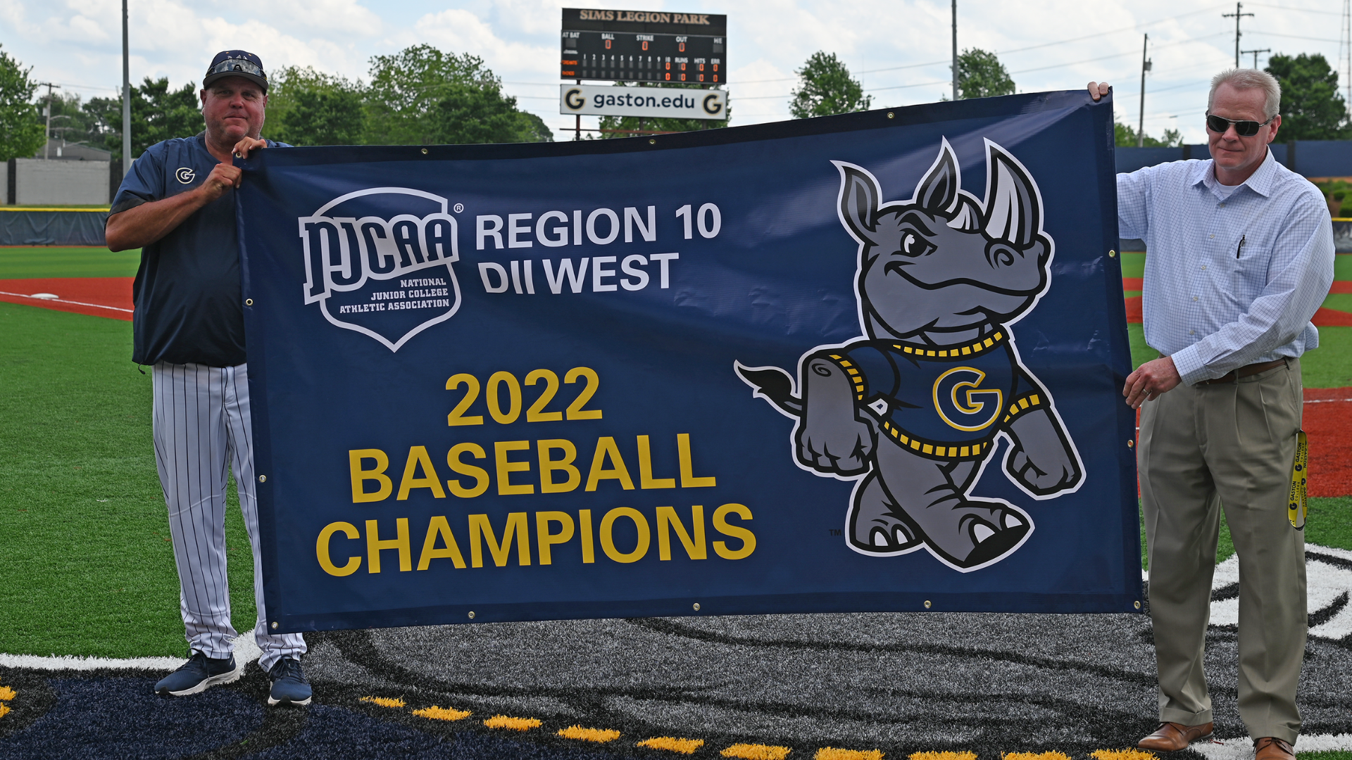 Gaston College baseball coach Shohn Doty (left) and president Dr. John Hauser with the school's 2022 Region 10 West Division championship banner.