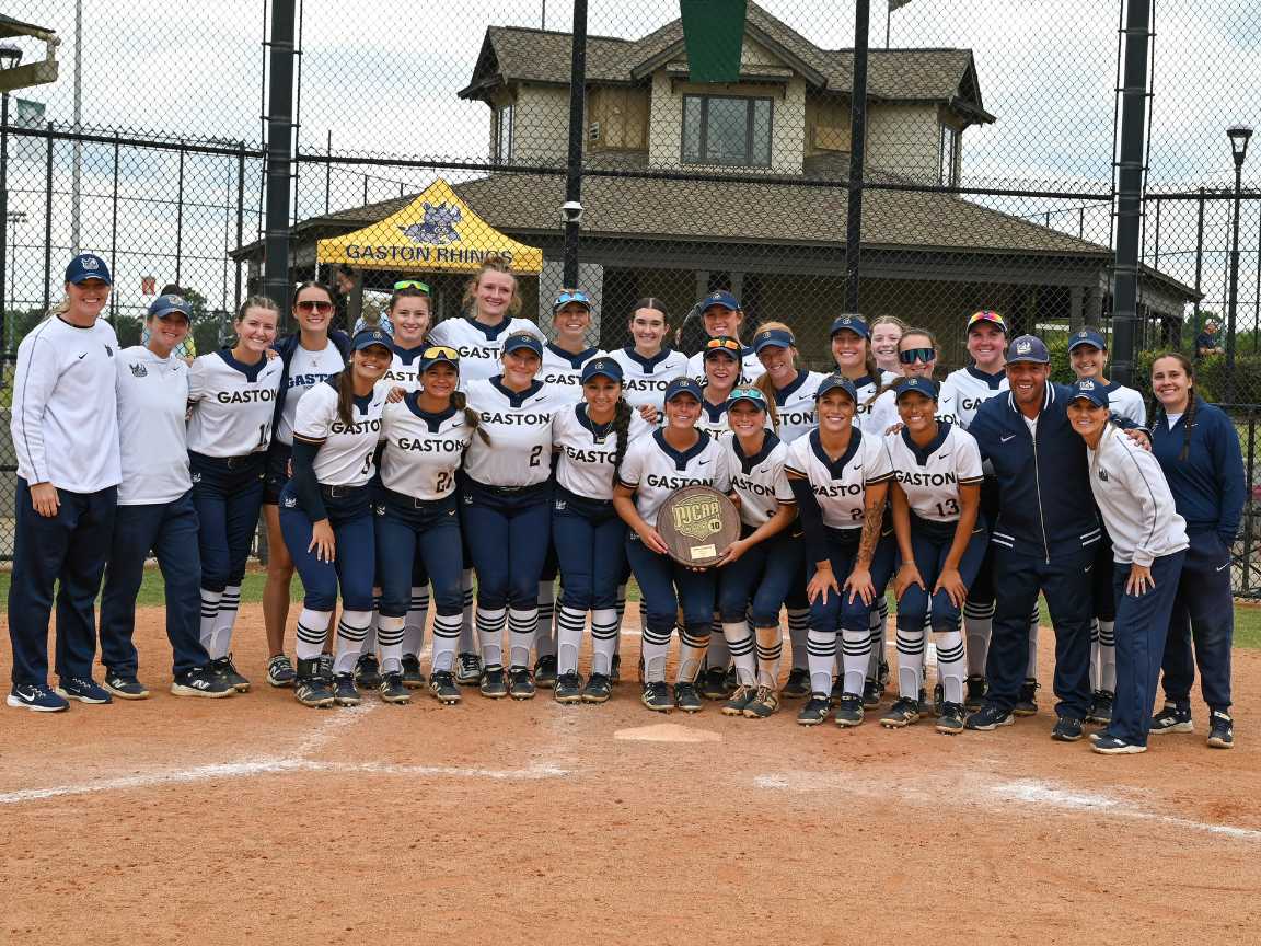 Gaston softball team poses as a group behind home plate holding the region 10 championship trophy.